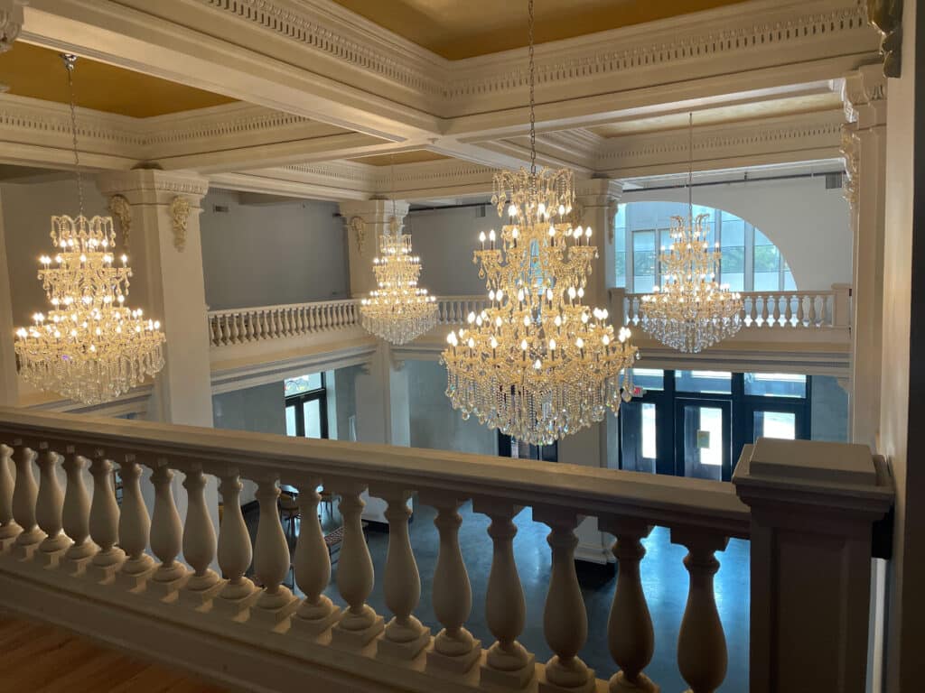 View of the grand ballroom at Katy Depot in Denison, TX, featuring multiple crystal chandeliers and historic white columns.