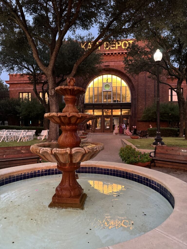 IMG_6221 Front fountain at Katy Depot in Denison, TX, with the historic building illuminated in the evening.