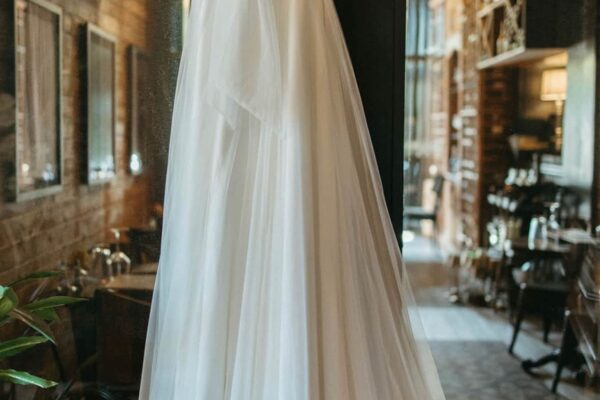 Wedding dress hanging with a bouquet of red roses outside Stafford House Provisions in Denison, TX.