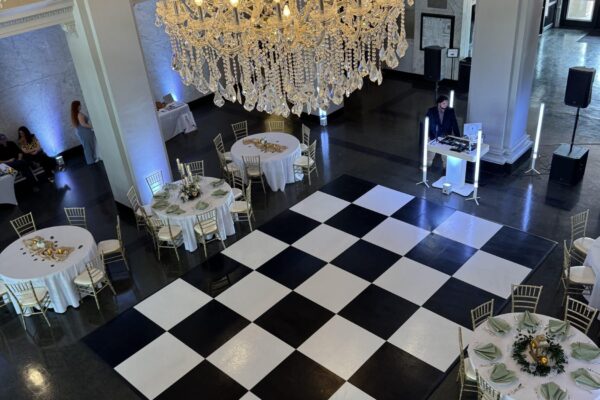 Wedding dance floor setup in the grand ballroom at Katy Depot in Denison, TX, surrounded by reception tables and chandeliers above.
